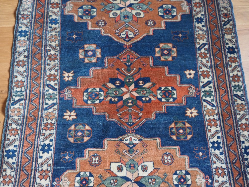 An antique Caucasian Derbent hand-knotted wool rug featuring three stepped medallions on a deep blue field with geometric borders. View IV