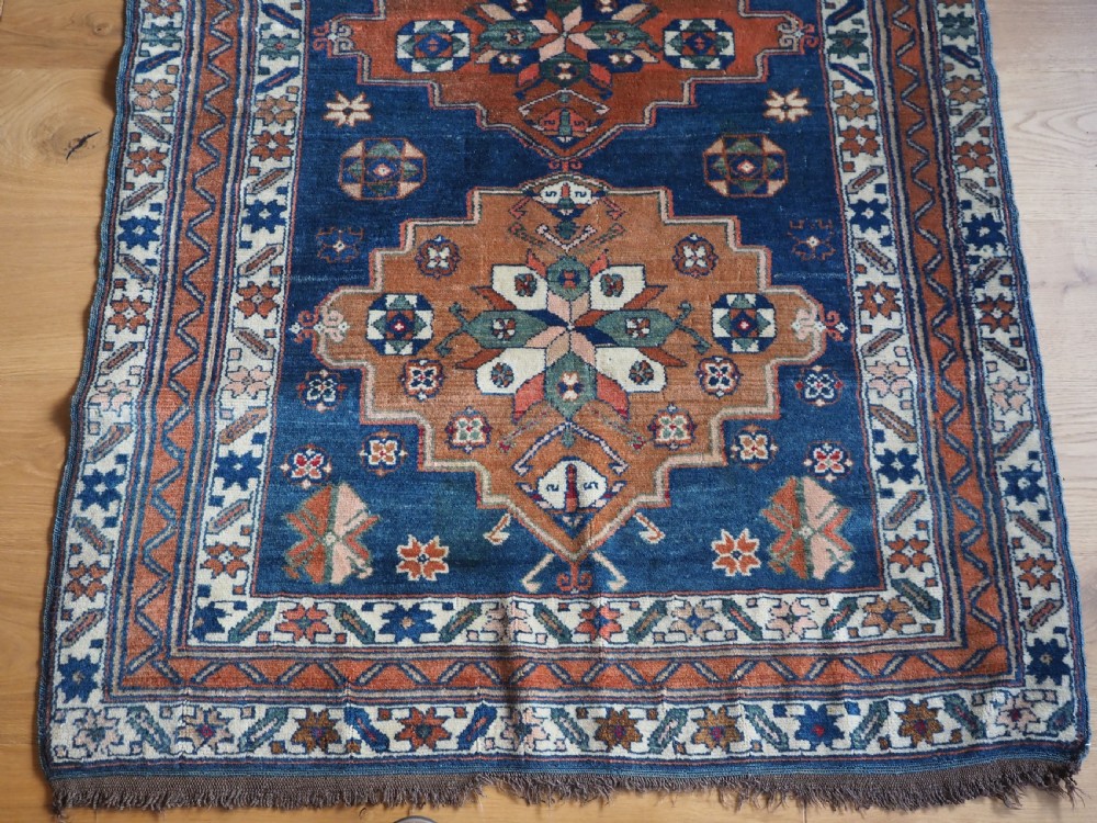 An antique Caucasian Derbent hand-knotted wool rug featuring three stepped medallions on a deep blue field with geometric borders. View V