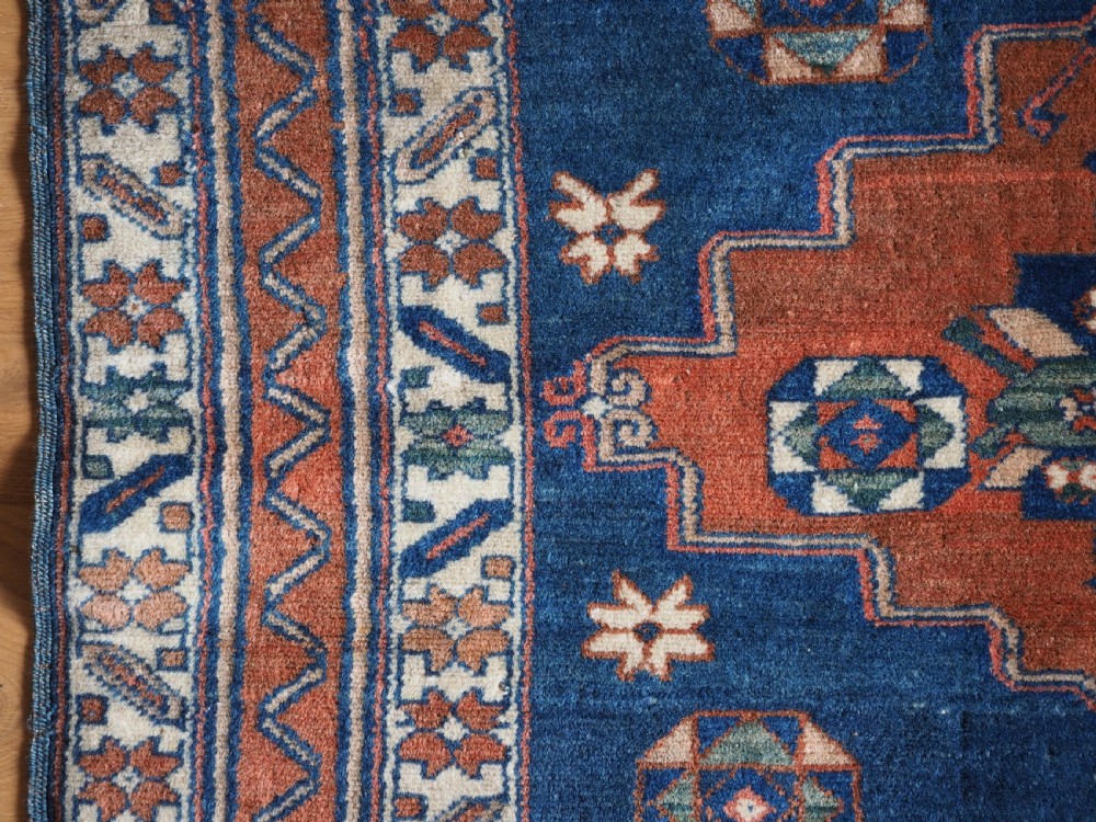 An antique Caucasian Derbent hand-knotted wool rug featuring three stepped medallions on a deep blue field with geometric borders. View VII