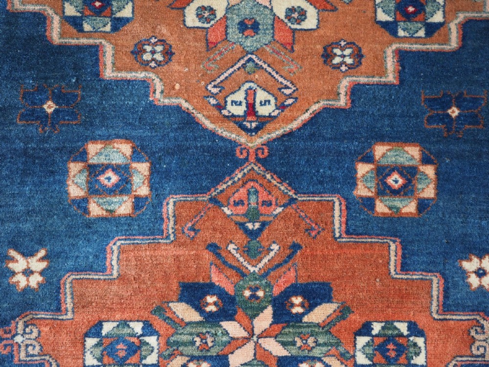 An antique Caucasian Derbent hand-knotted wool rug featuring three stepped medallions on a deep blue field with geometric borders. View IX