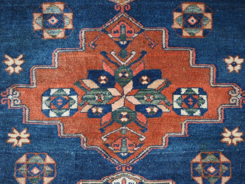 An antique Caucasian Derbent hand-knotted wool rug featuring three stepped medallions on a deep blue field with geometric borders. View X