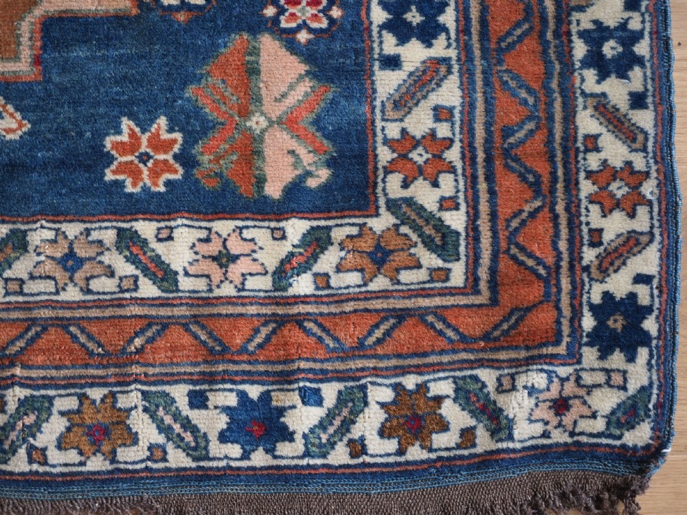 An antique Caucasian Derbent hand-knotted wool rug featuring three stepped medallions on a deep blue field with geometric borders. View XIII