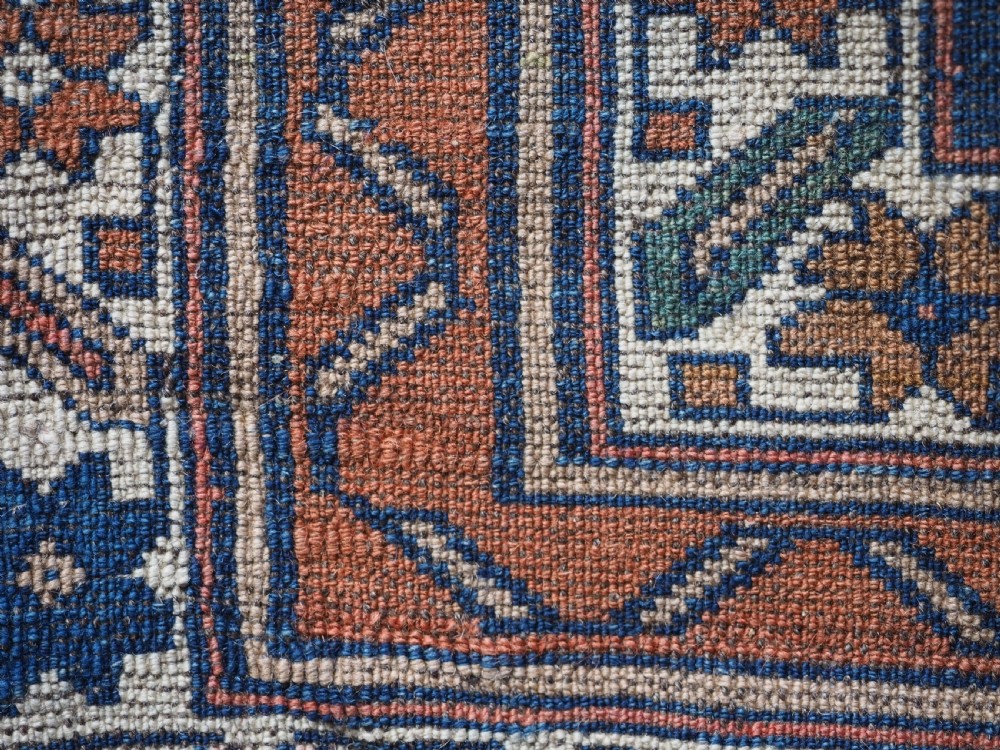 An antique Caucasian Derbent hand-knotted wool rug featuring three stepped medallions on a deep blue field with geometric borders. View XIV