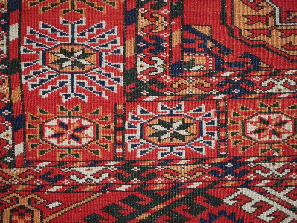 An antique rectangular hand-knotted Tekke Turkmen rug featuring repeating octagonal gol motifs on a deep red wool field framed by geometric borders. View XII