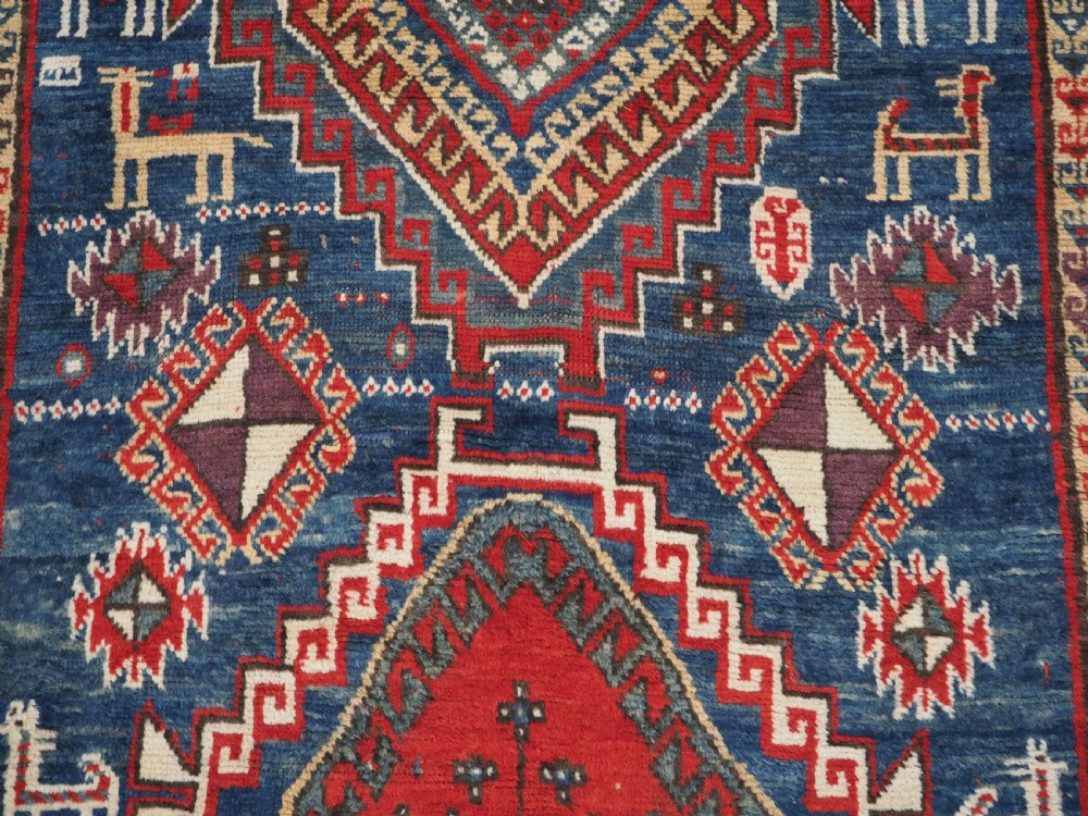 An antique Caucasian Bordjalou Kazak rug featuring a central navy blue field with two large red diamond medallions, zoomorphic animal motifs, and multi-layered geometric borders. View XI