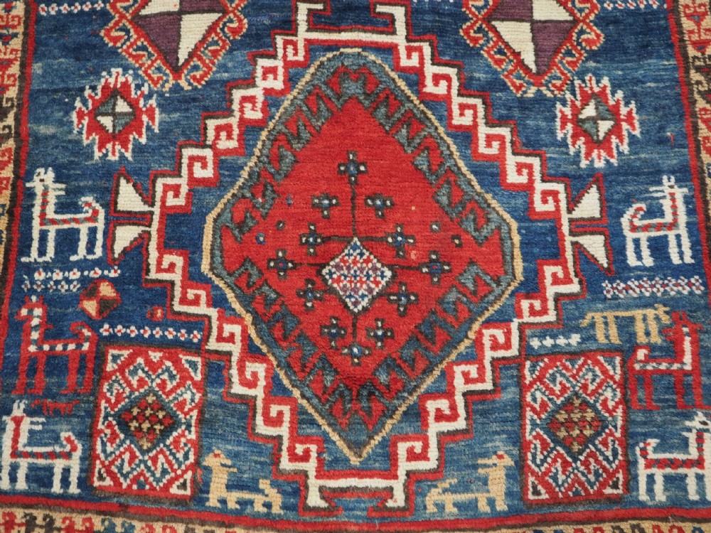 An antique Caucasian Bordjalou Kazak rug featuring a central navy blue field with two large red diamond medallions, zoomorphic animal motifs, and multi-layered geometric borders. View XIV