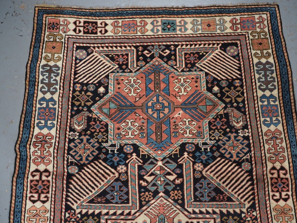 An antique Caucasian Akstafa wool rug runner featuring geometric star medallions and stylised peacock motifs on a dark navy field with a decorative border. View III