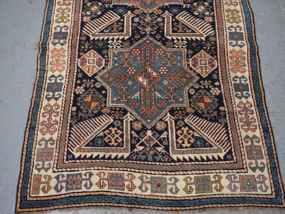 An antique Caucasian Akstafa wool rug runner featuring geometric star medallions and stylised peacock motifs on a dark navy field with a decorative border. View VI