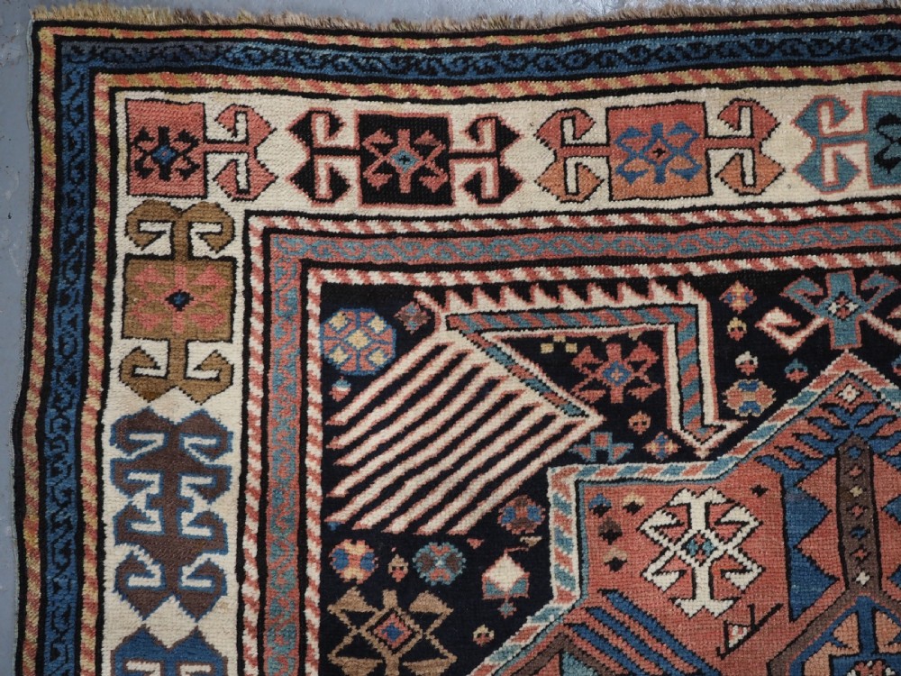 An antique Caucasian Akstafa wool rug runner featuring geometric star medallions and stylised peacock motifs on a dark navy field with a decorative border. View VII