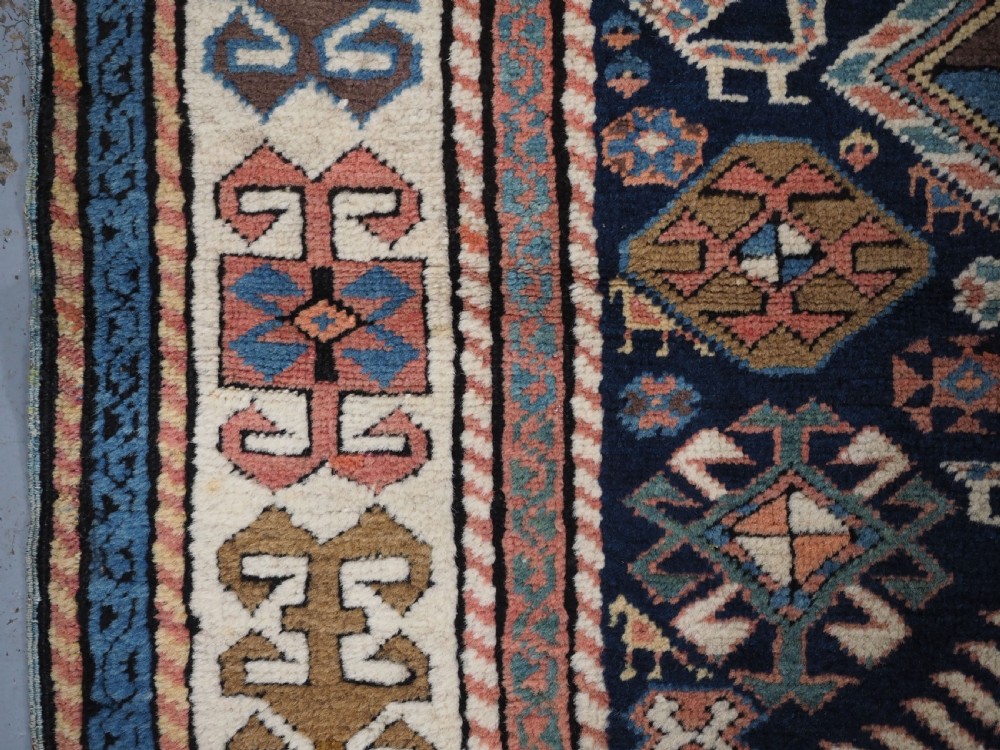 An antique Caucasian Akstafa wool rug runner featuring geometric star medallions and stylised peacock motifs on a dark navy field with a decorative border. View VIII