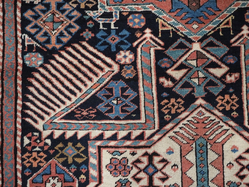 An antique Caucasian Akstafa wool rug runner featuring geometric star medallions and stylised peacock motifs on a dark navy field with a decorative border. View X