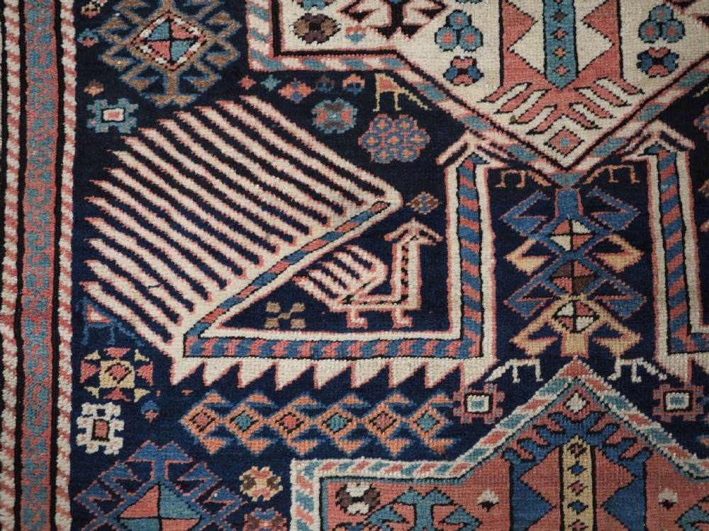 An antique Caucasian Akstafa wool rug runner featuring geometric star medallions and stylised peacock motifs on a dark navy field with a decorative border. View XII