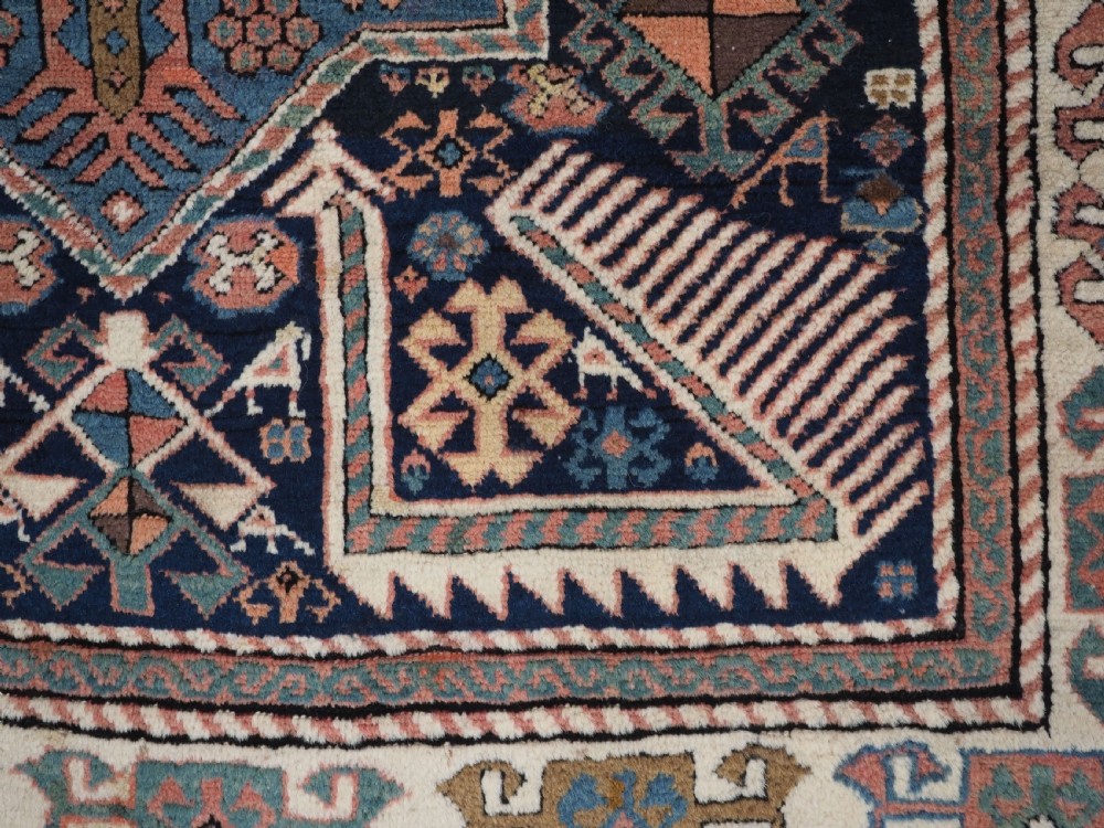 An antique Caucasian Akstafa wool rug runner featuring geometric star medallions and stylised peacock motifs on a dark navy field with a decorative border. View XVI