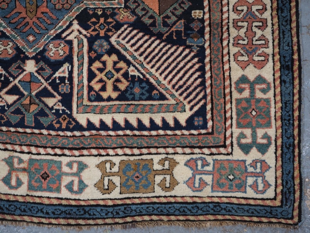 An antique Caucasian Akstafa wool rug runner featuring geometric star medallions and stylised peacock motifs on a dark navy field with a decorative border. View XVII