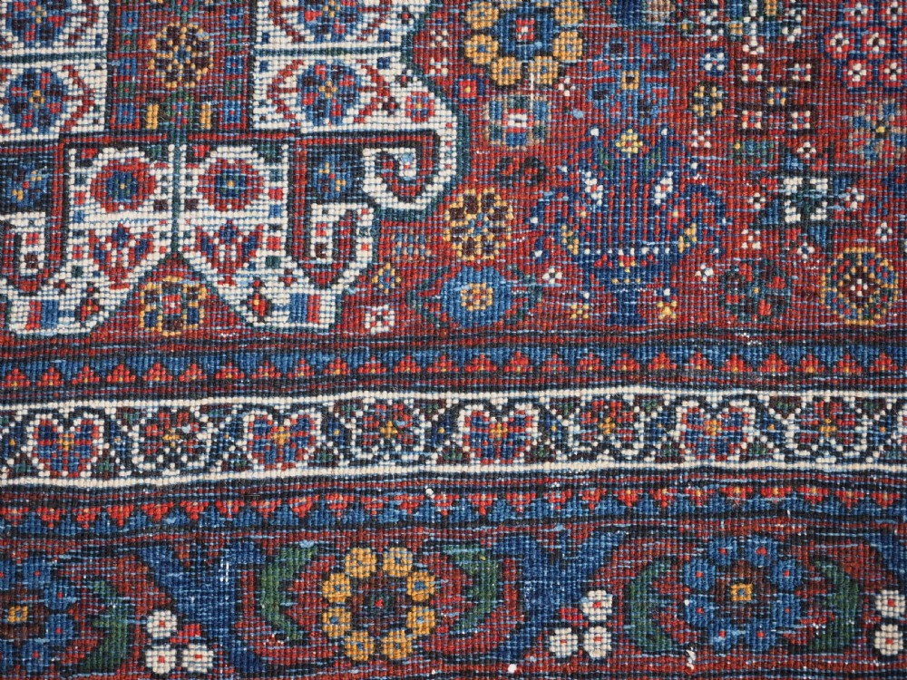 A rectangular hand-knotted antique Abadeh rug featuring a navy blue central field with a diamond medallion and rust red geometric spandrels. View XIV