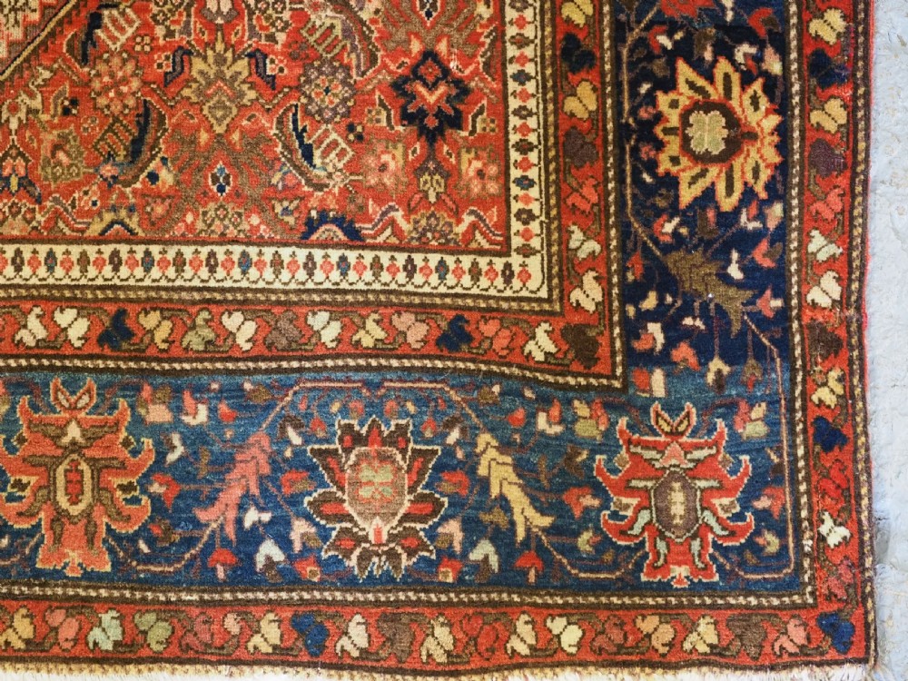An antique Persian Sarouk rug featuring a repeating central boteh pattern framed by detailed floral borders in shades of terracotta red, cream, and navy blue. View XII