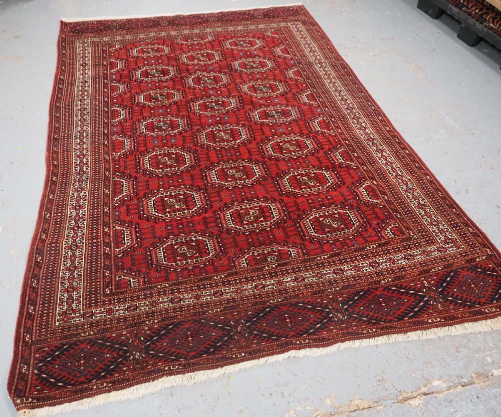 An antique deep red Yomut Turkmen wool rug featuring repeating octagonal guls and intricate geometric borders. View II