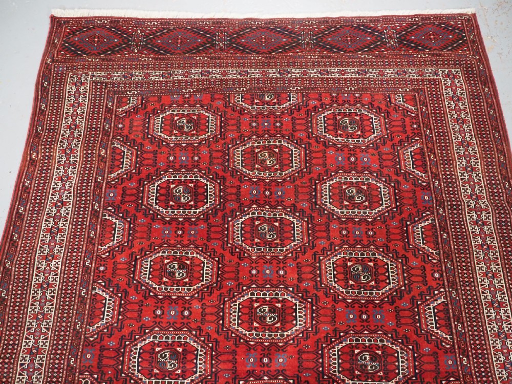 An antique deep red Yomut Turkmen wool rug featuring repeating octagonal guls and intricate geometric borders. View III