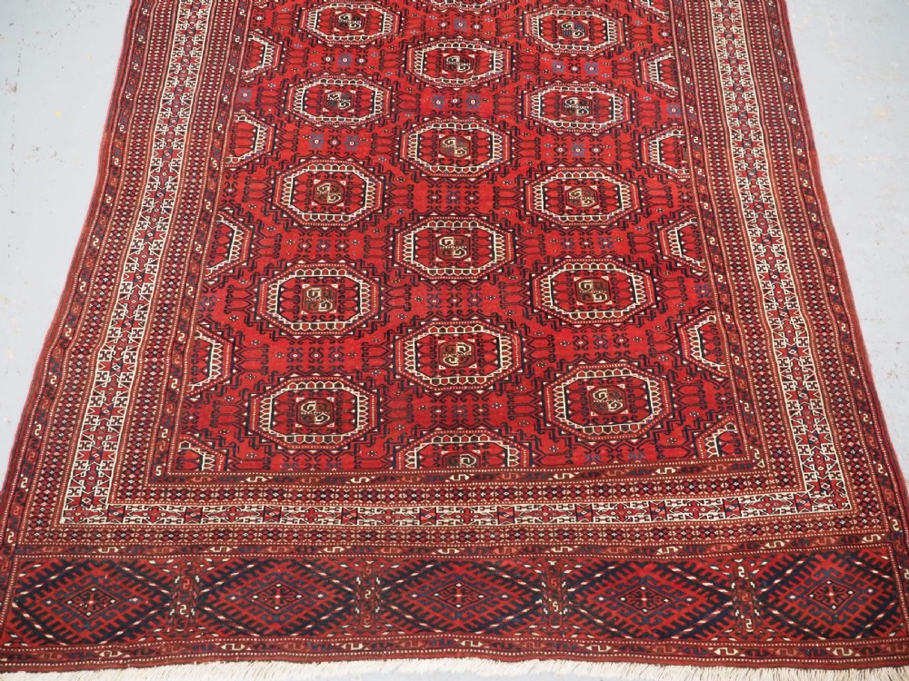 An antique deep red Yomut Turkmen wool rug featuring repeating octagonal guls and intricate geometric borders. View V