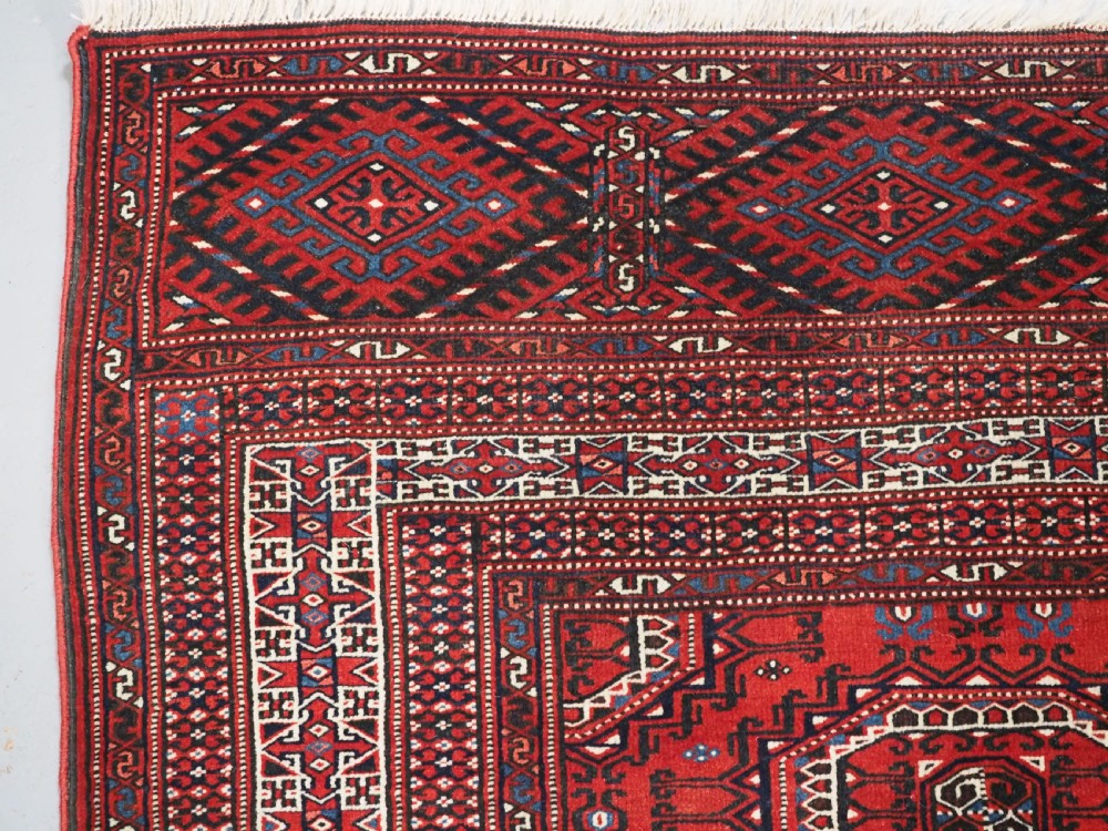 An antique deep red Yomut Turkmen wool rug featuring repeating octagonal guls and intricate geometric borders. View VI