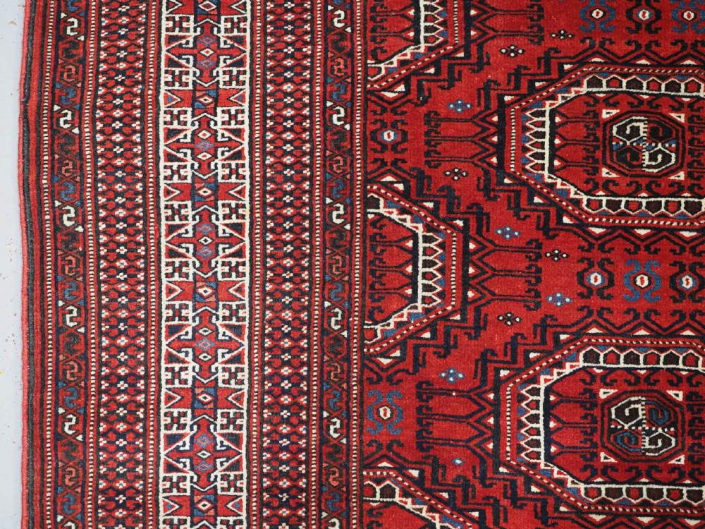 An antique deep red Yomut Turkmen wool rug featuring repeating octagonal guls and intricate geometric borders. View VII
