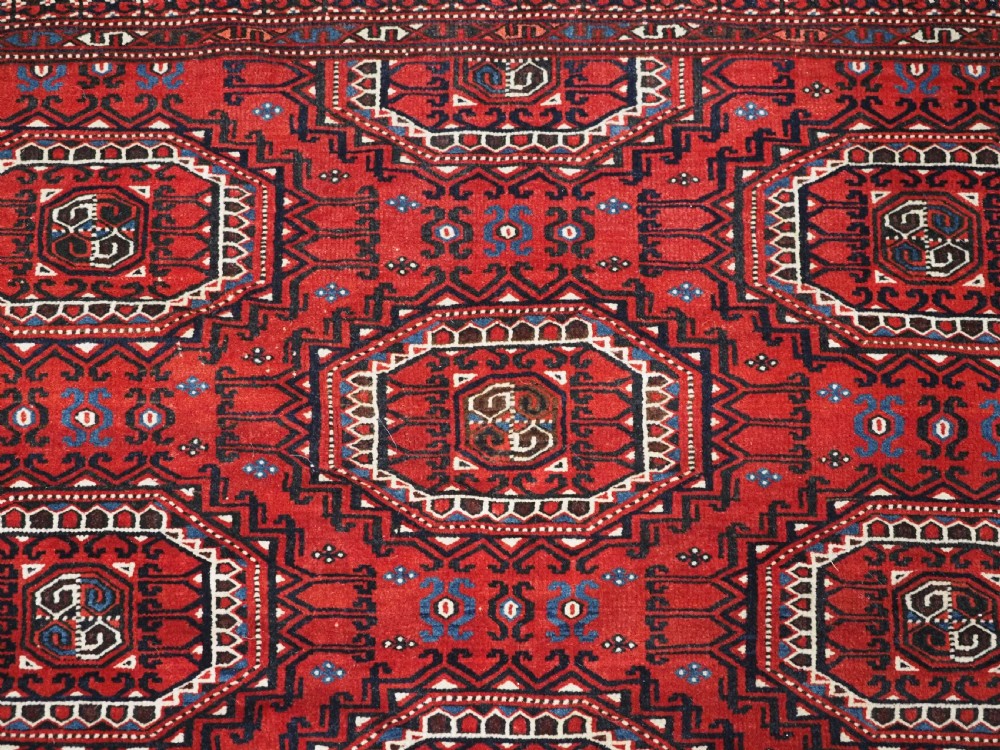 An antique deep red Yomut Turkmen wool rug featuring repeating octagonal guls and intricate geometric borders. View VIII