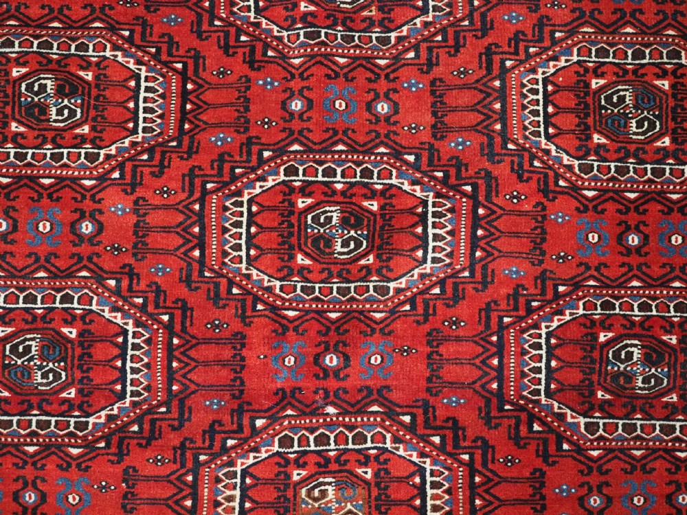 An antique deep red Yomut Turkmen wool rug featuring repeating octagonal guls and intricate geometric borders. View IX