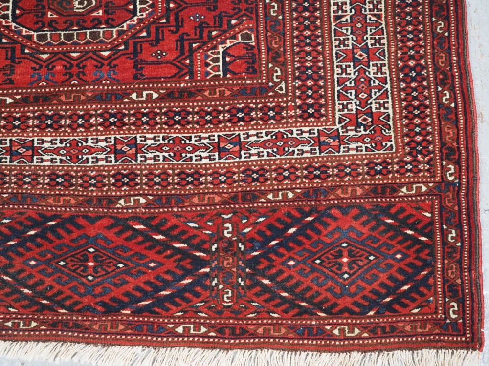 An antique deep red Yomut Turkmen wool rug featuring repeating octagonal guls and intricate geometric borders. View XI