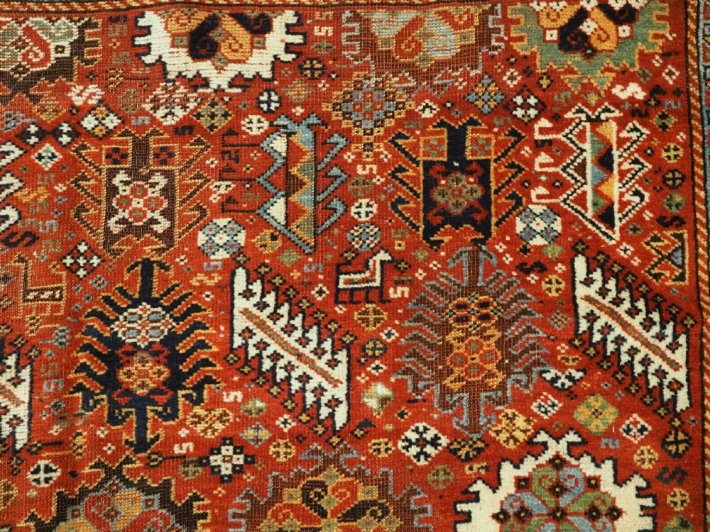 An antique South Persian Shekarlu Qashqai wool rug featuring a red field with dense geometric tribal motifs surrounded by an ivory patterned border. View IX