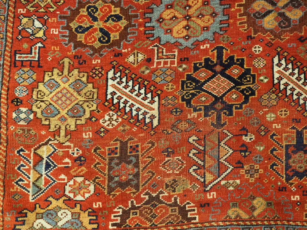 An antique South Persian Shekarlu Qashqai wool rug featuring a red field with dense geometric tribal motifs surrounded by an ivory patterned border. View XI