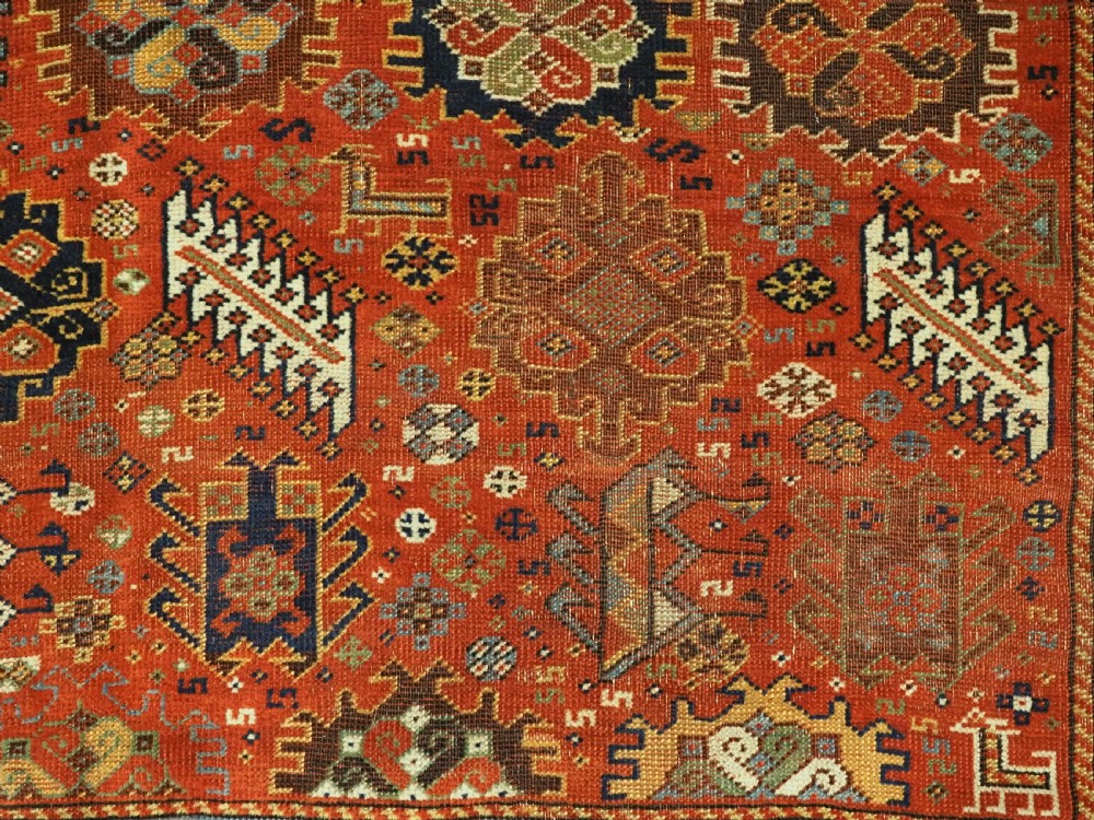 An antique South Persian Shekarlu Qashqai wool rug featuring a red field with dense geometric tribal motifs surrounded by an ivory patterned border. View XII