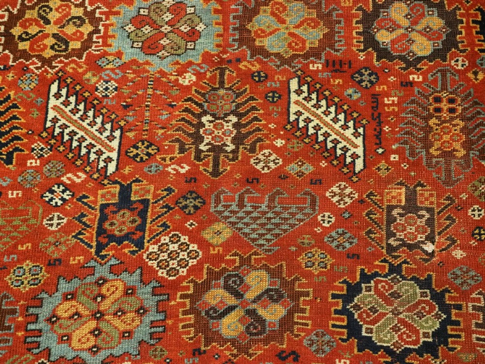 An antique South Persian Shekarlu Qashqai wool rug featuring a red field with dense geometric tribal motifs surrounded by an ivory patterned border. View XIII