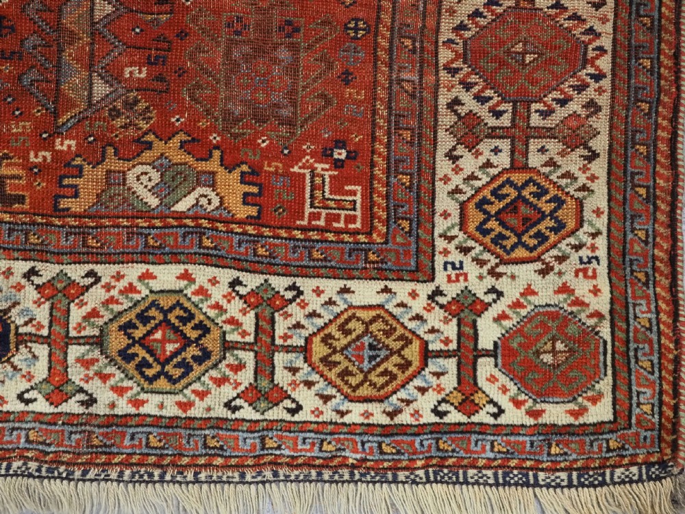 An antique South Persian Shekarlu Qashqai wool rug featuring a red field with dense geometric tribal motifs surrounded by an ivory patterned border. View XIV