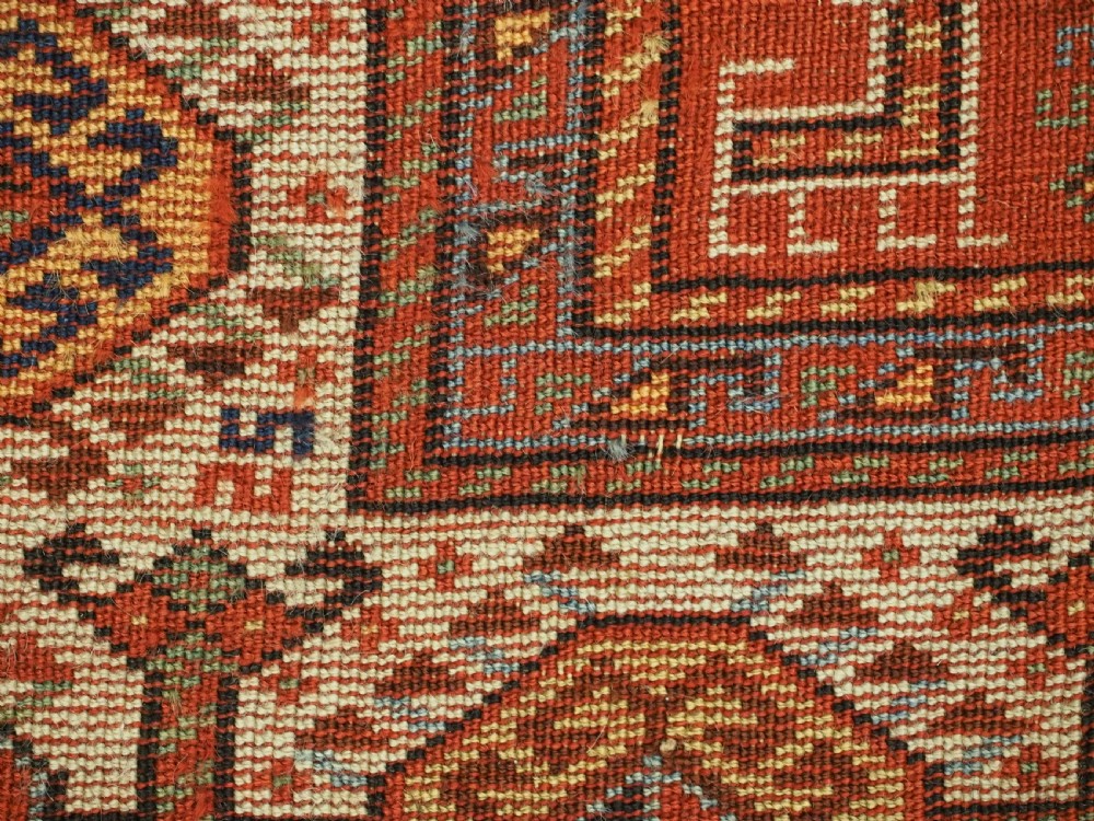An antique South Persian Shekarlu Qashqai wool rug featuring a red field with dense geometric tribal motifs surrounded by an ivory patterned border. View XV