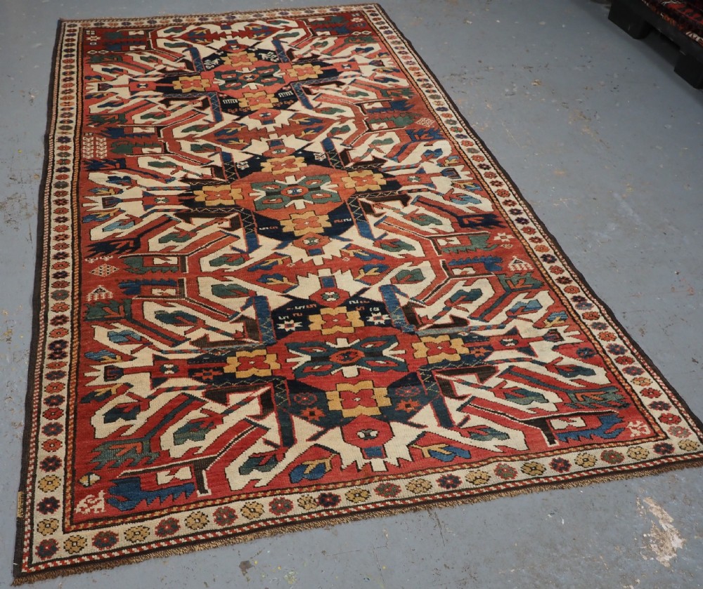 An antique Caucasian Chelaberd Kazak wool rug featuring three prominent sunburst medallions in cream, navy, and green set against a bold red ground with geometric borders. View II