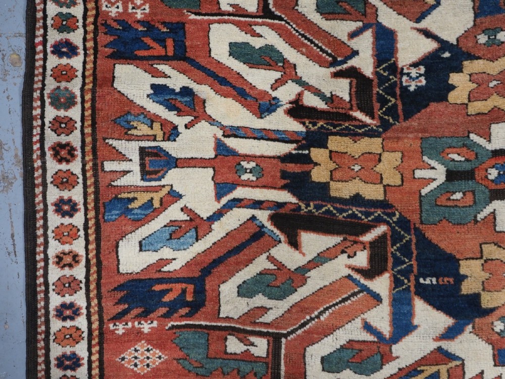 An antique Caucasian Chelaberd Kazak wool rug featuring three prominent sunburst medallions in cream, navy, and green set against a bold red ground with geometric borders. View VII