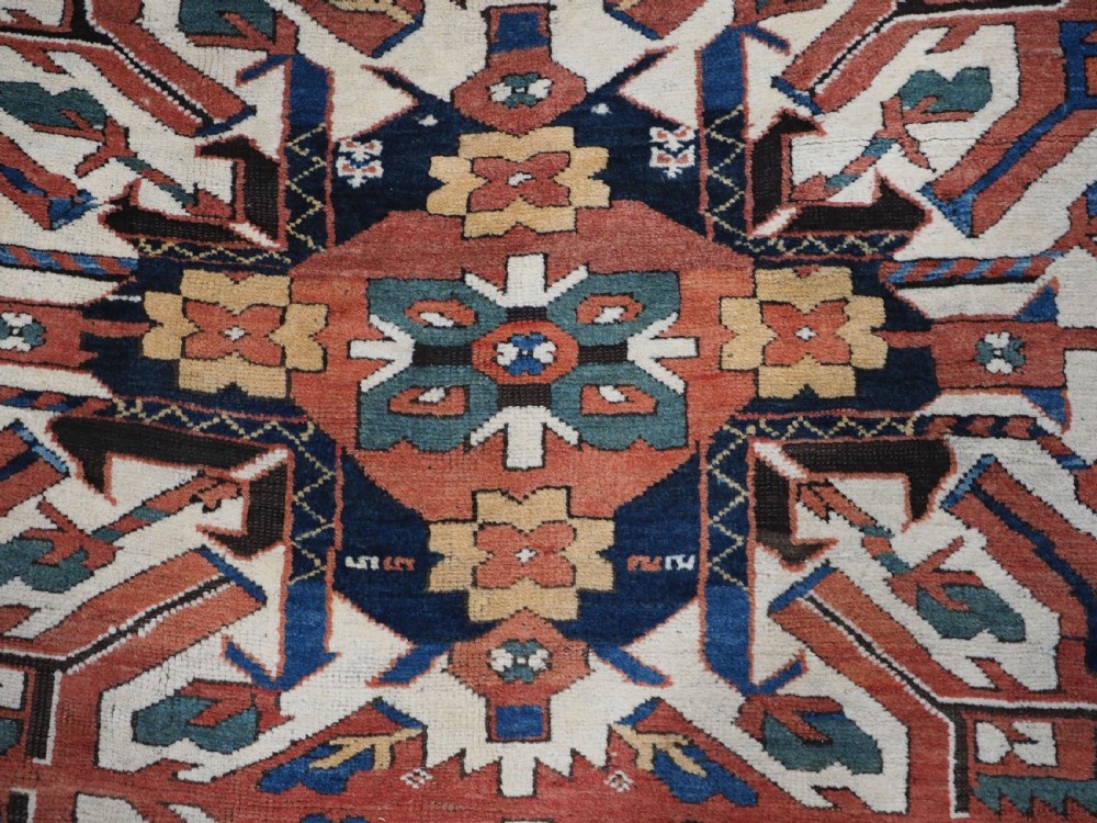 An antique Caucasian Chelaberd Kazak wool rug featuring three prominent sunburst medallions in cream, navy, and green set against a bold red ground with geometric borders. View VIII