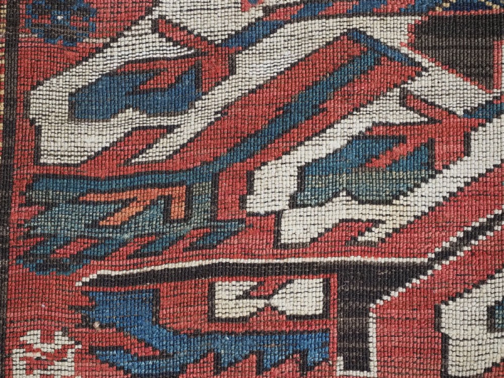 An antique Caucasian Chelaberd Kazak wool rug featuring three prominent sunburst medallions in cream, navy, and green set against a bold red ground with geometric borders. View X
