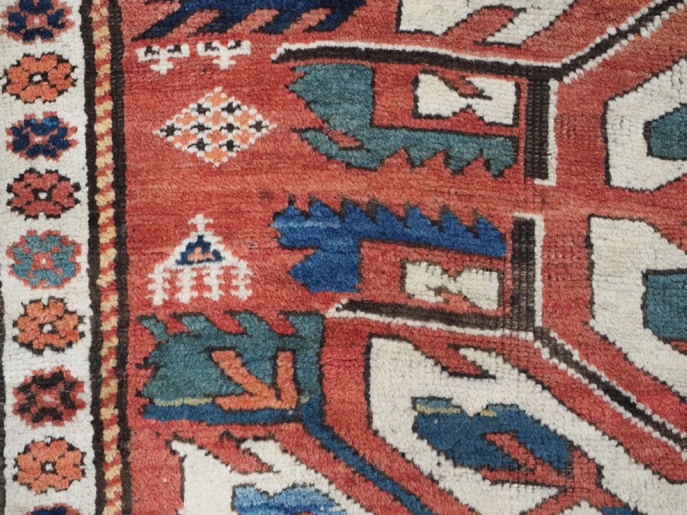An antique Caucasian Chelaberd Kazak wool rug featuring three prominent sunburst medallions in cream, navy, and green set against a bold red ground with geometric borders. View XII