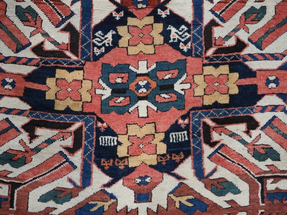An antique Caucasian Chelaberd Kazak wool rug featuring three prominent sunburst medallions in cream, navy, and green set against a bold red ground with geometric borders. View XIII