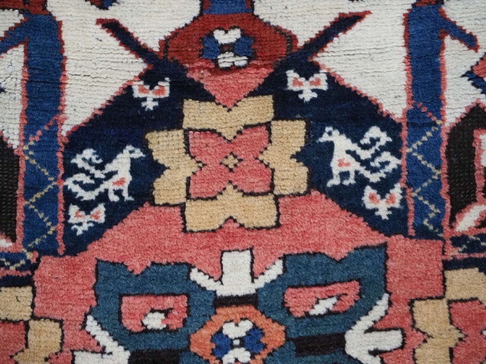 An antique Caucasian Chelaberd Kazak wool rug featuring three prominent sunburst medallions in cream, navy, and green set against a bold red ground with geometric borders. View XIV