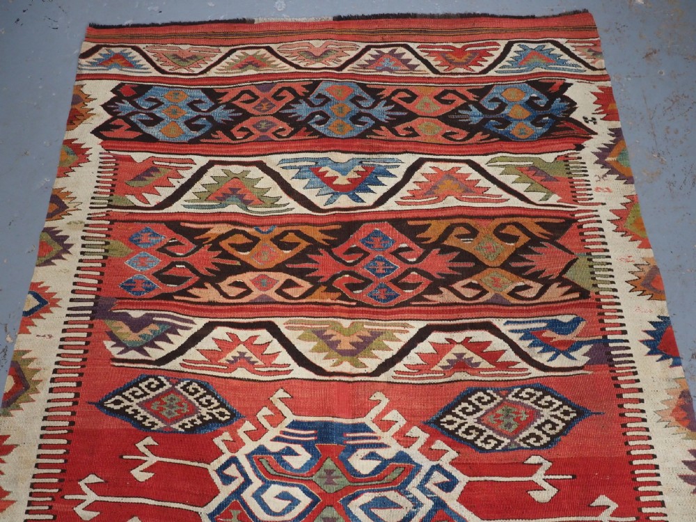 A long hand-woven Turkish Mut kilim rug featuring bold red, navy, brown, and cream geometric motifs arranged in horizontal bands. View III