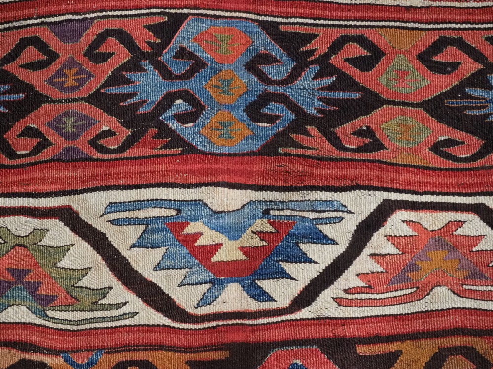 A long hand-woven Turkish Mut kilim rug featuring bold red, navy, brown, and cream geometric motifs arranged in horizontal bands. View VI
