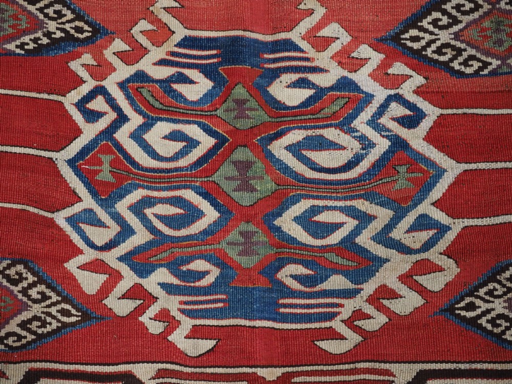 A long hand-woven Turkish Mut kilim rug featuring bold red, navy, brown, and cream geometric motifs arranged in horizontal bands. View IX
