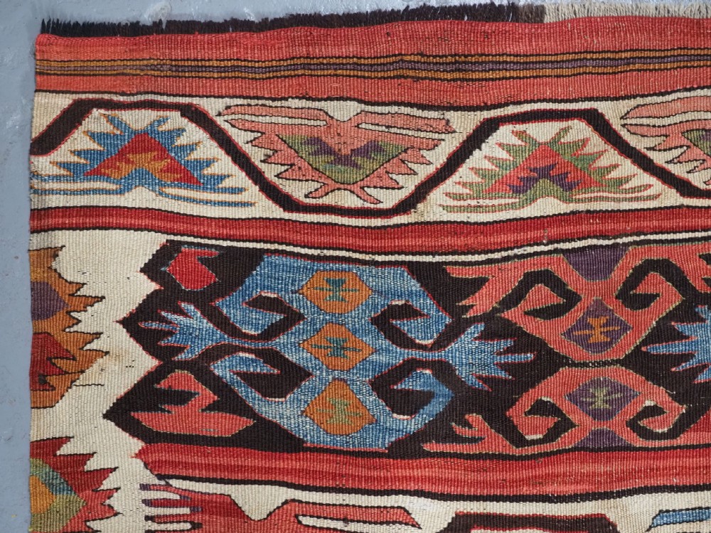 A long hand-woven Turkish Mut kilim rug featuring bold red, navy, brown, and cream geometric motifs arranged in horizontal bands. View XII
