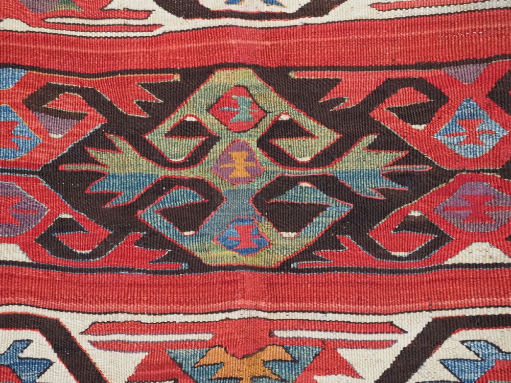 A long hand-woven Turkish Mut kilim rug featuring bold red, navy, brown, and cream geometric motifs arranged in horizontal bands. View XIV