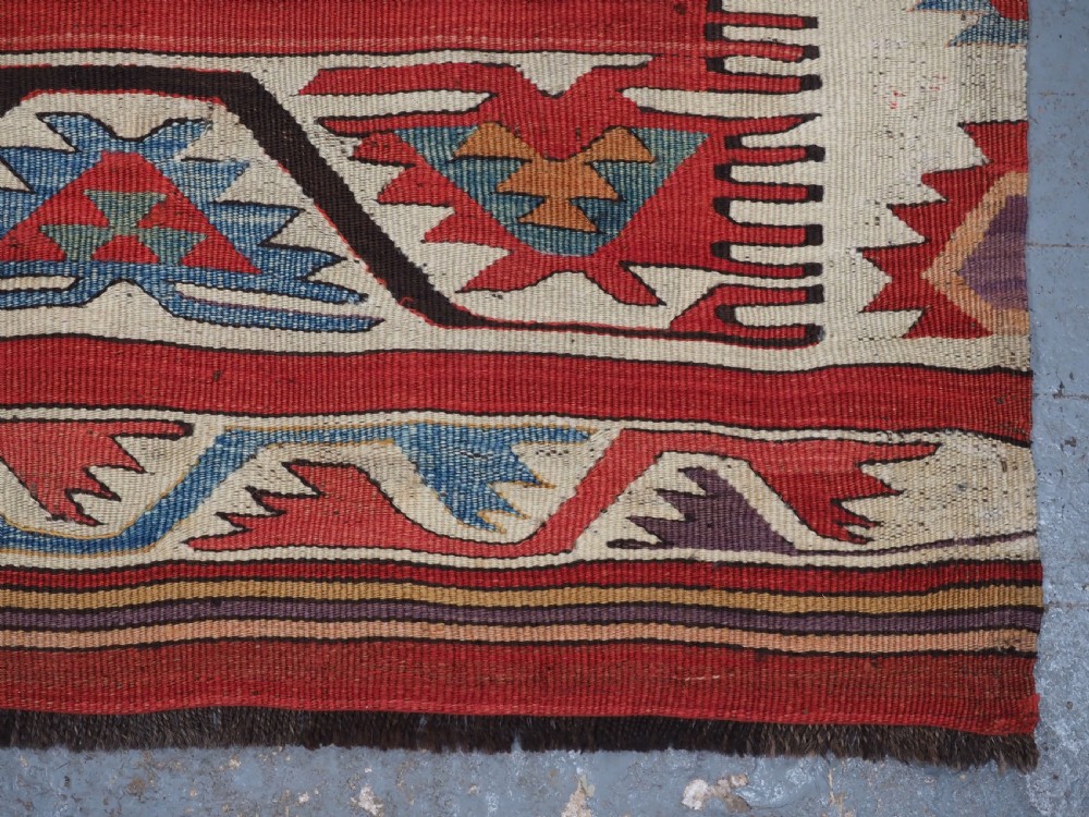 A long hand-woven Turkish Mut kilim rug featuring bold red, navy, brown, and cream geometric motifs arranged in horizontal bands. View XV