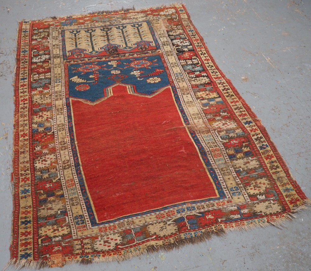 An antique hand-knotted Turkish Ladik prayer rug featuring a central red arched mihrab niche, blue spandrels, stylized floral panels, and a patterned multi-tiered border. View II
