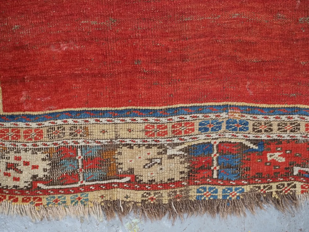 An antique hand-knotted Turkish Ladik prayer rug featuring a central red arched mihrab niche, blue spandrels, stylized floral panels, and a patterned multi-tiered border. View XIV