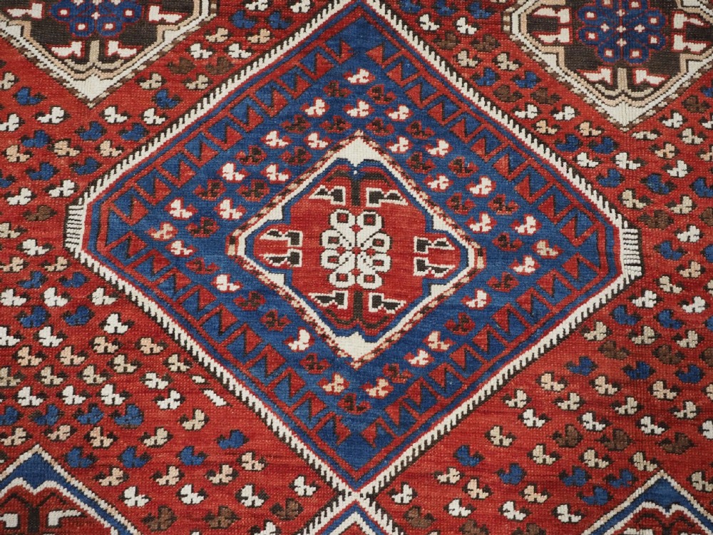 An antique hand-knotted Caucasian Shirvan Baku Khila wool rug featuring geometric diamond medallions on a red ground with navy blue and ivory borders. View XI